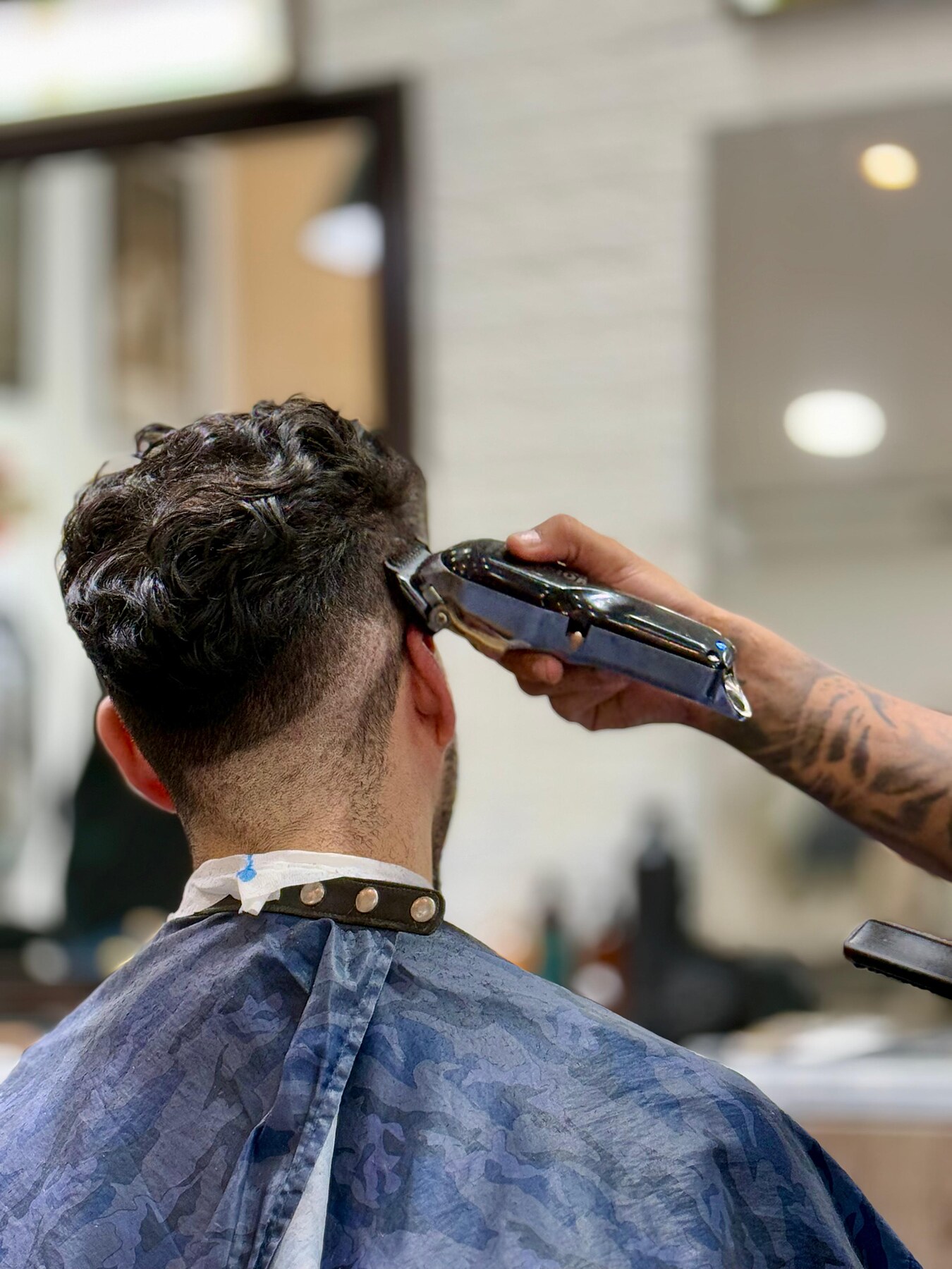 Barbero de La Guarida terminando un corte con máquina
